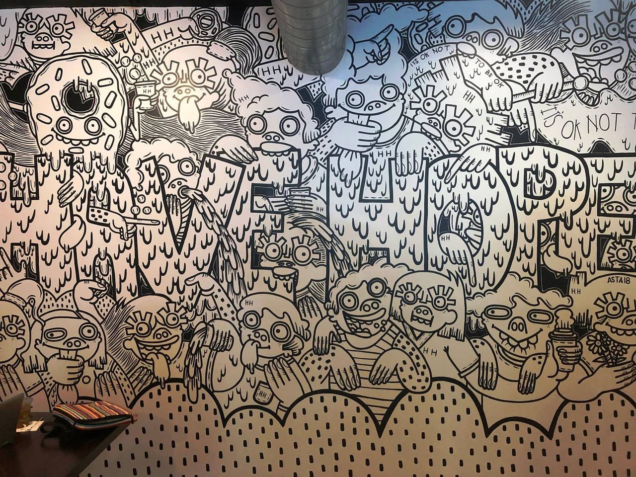 Black-and-white cartoon mural of crowded faces spelling out a message
