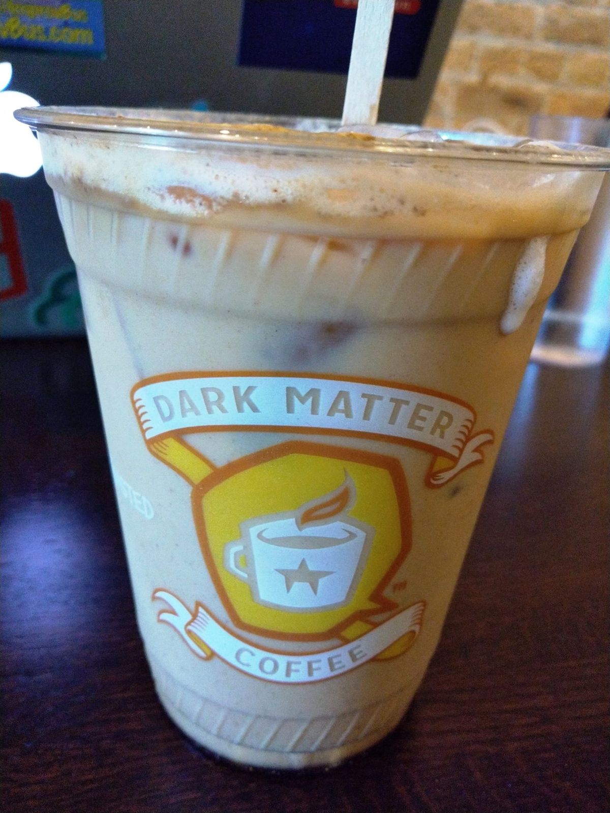 Iced coffee in a clear Dark Matter Coffee cup with wooden stirrer