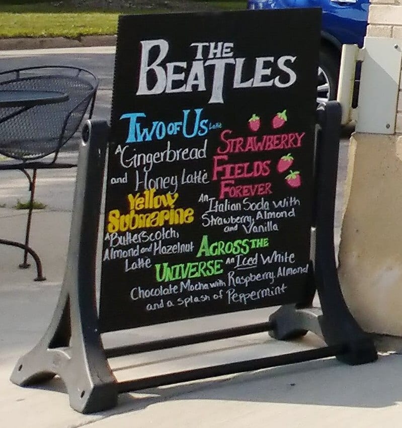Sidewalk chalkboard listing Beatles themed latte specials