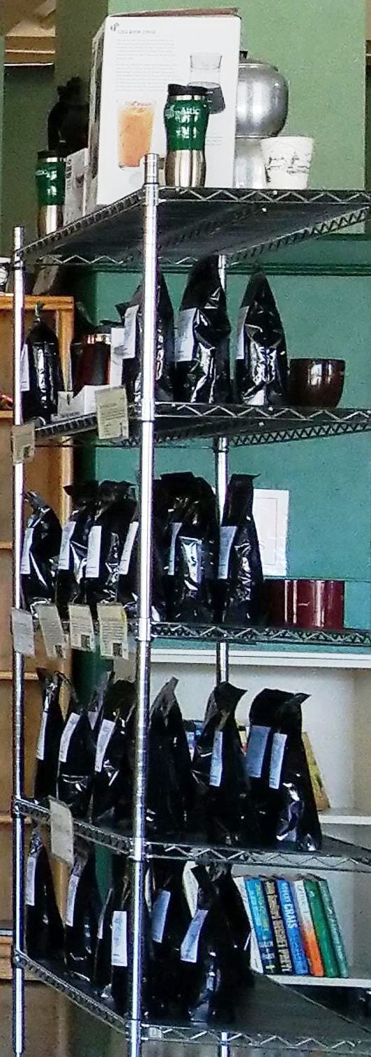 Chrome shelving stacked with black bags of whole beans