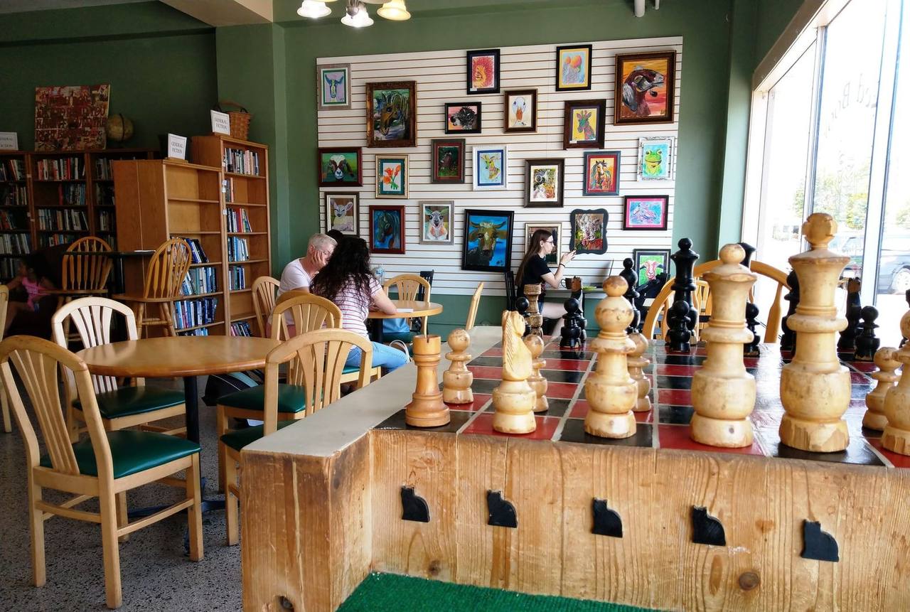 Giant chess set beside cafe tables and a wall of animal paintings