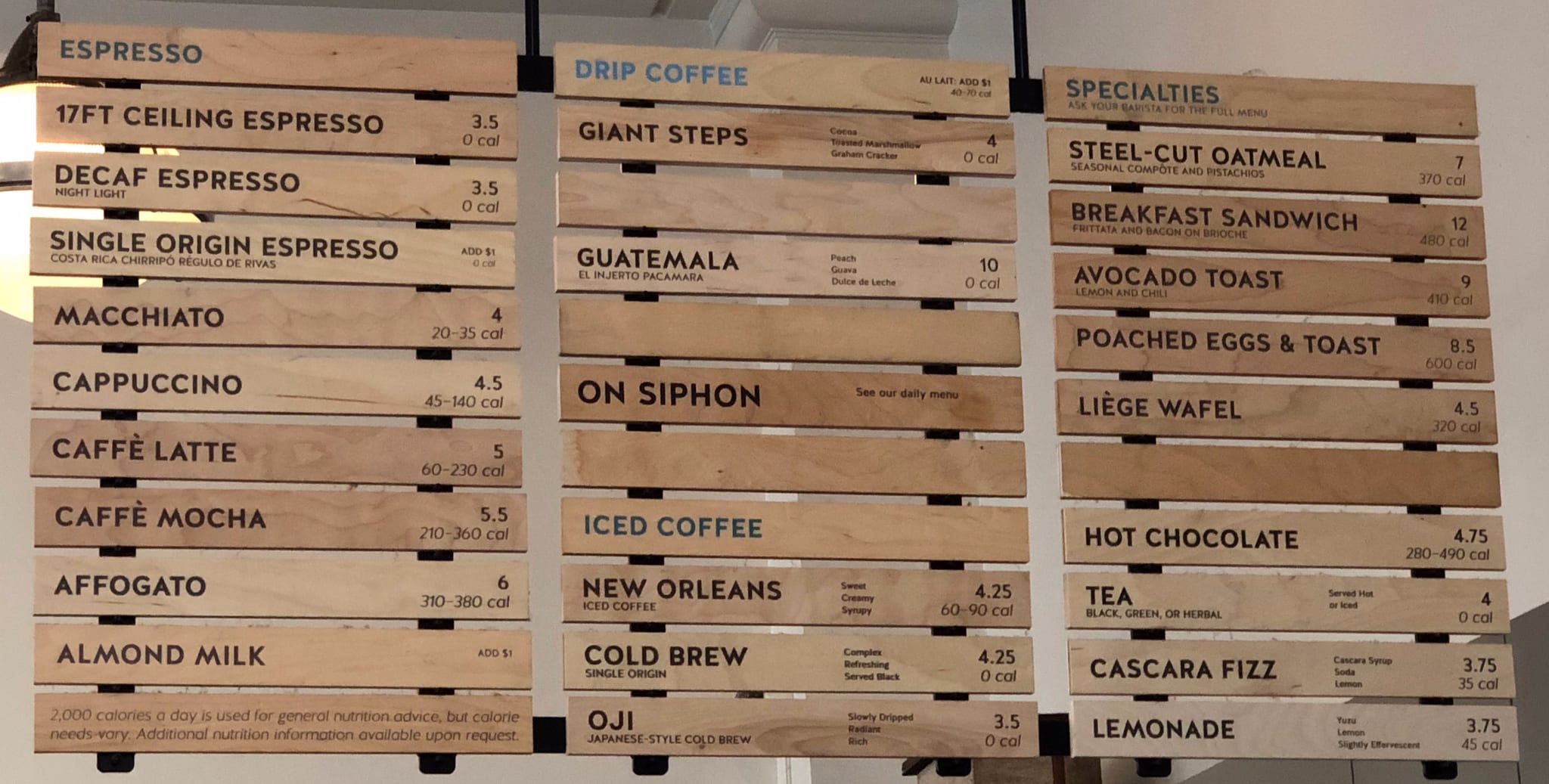 Wooden slat menu boards listing espresso, drip coffee, and food specialties